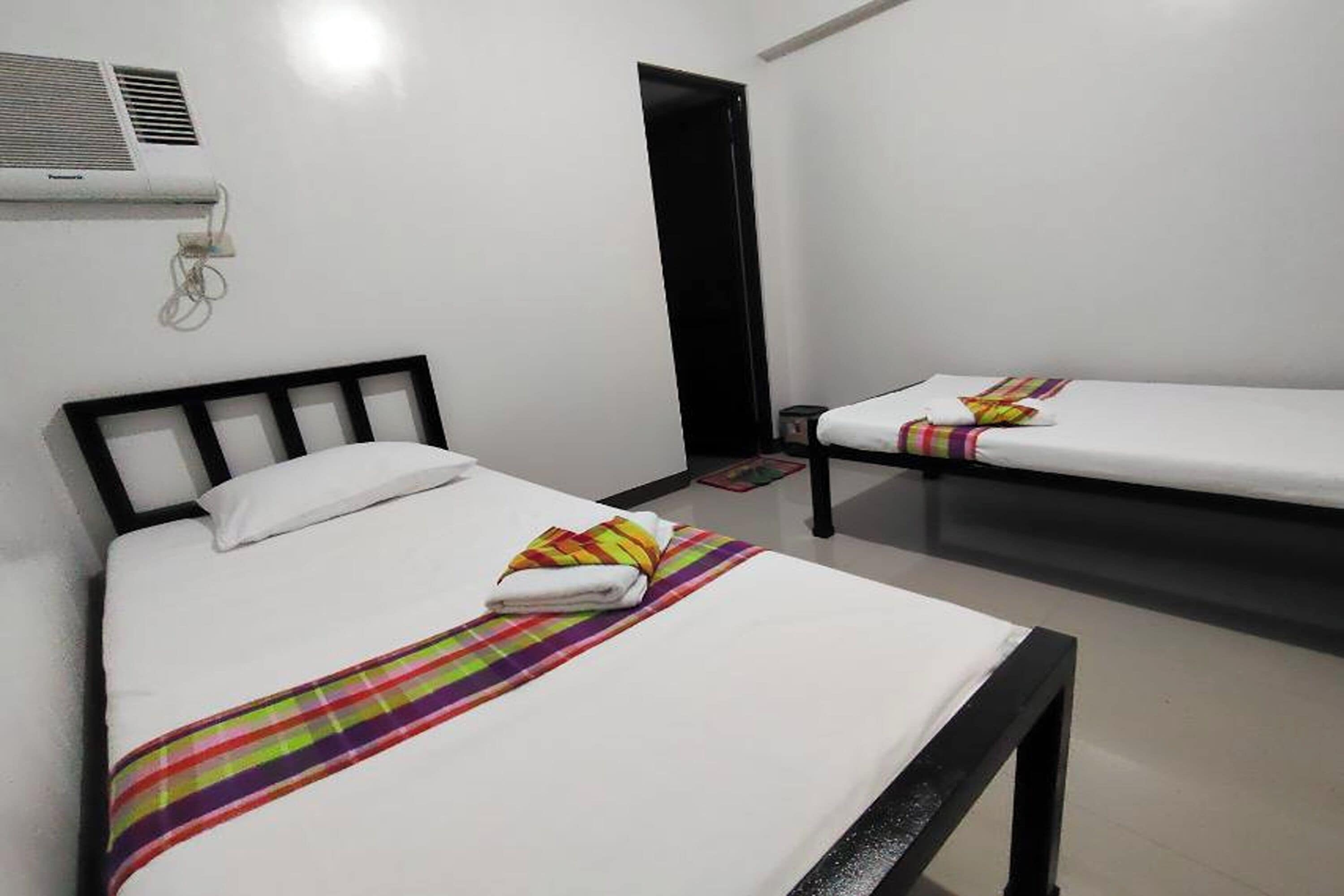Una habitación de hotel con dos camas individuales, una mesita y una puerta.