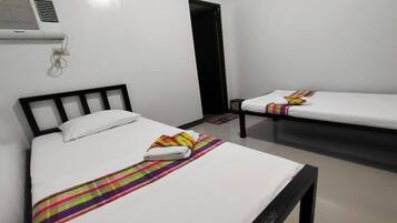 Una habitación de hotel con dos camas individuales, una mesita y una puerta.