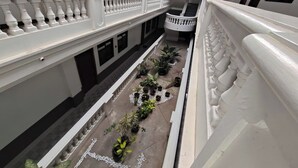 A courtyard with a white balustrade, potted plants, and a spiral staircase. - Benediktus Pilgerhaus Inn (Vigan)