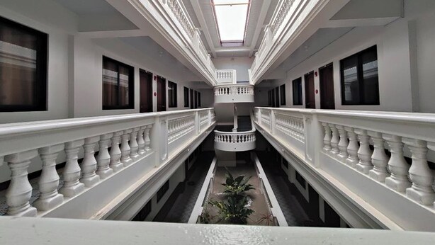 A corridor with white balustrades, a central staircase, and a skylight. - Benediktus Pilgerhaus Inn (Vigan)