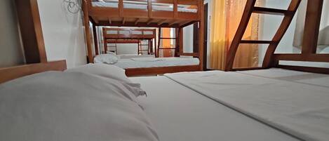 A room with bunk beds, a window with curtains, and a ceiling light.