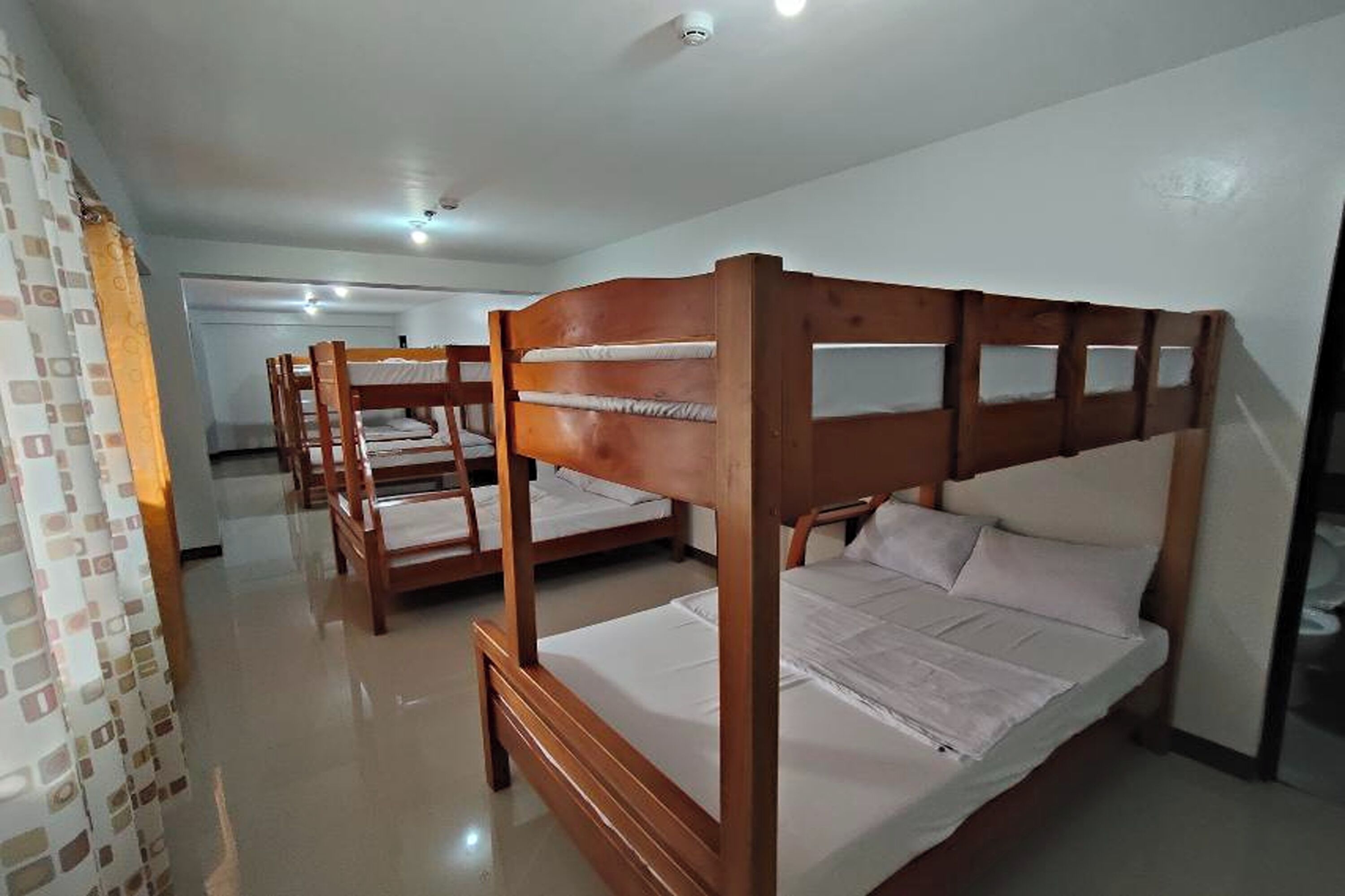 A room with bunk beds, a tiled floor, and a white wall.