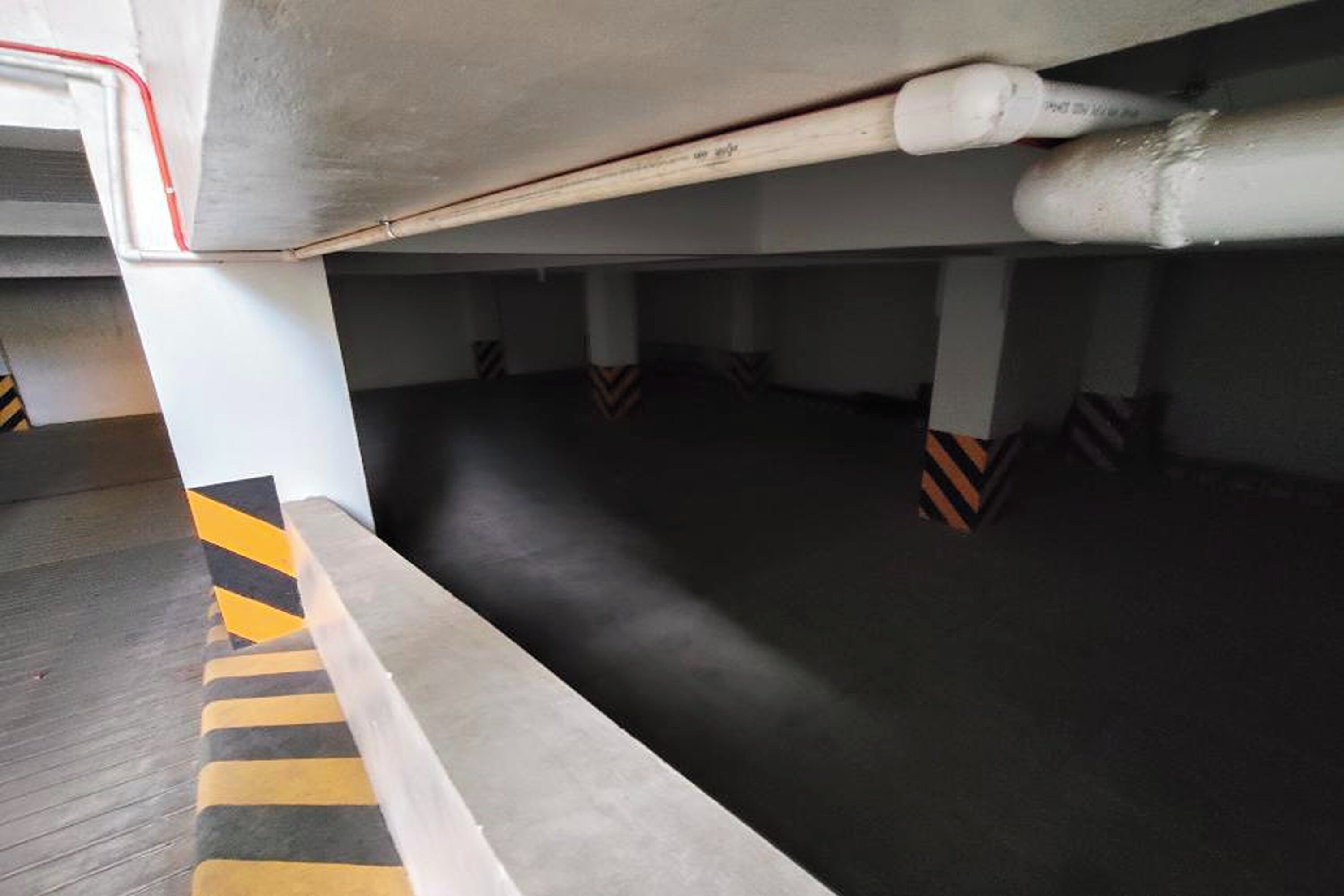 Un estacionamiento subterráneo con pilares de concreto y una línea de seguridad rayada.