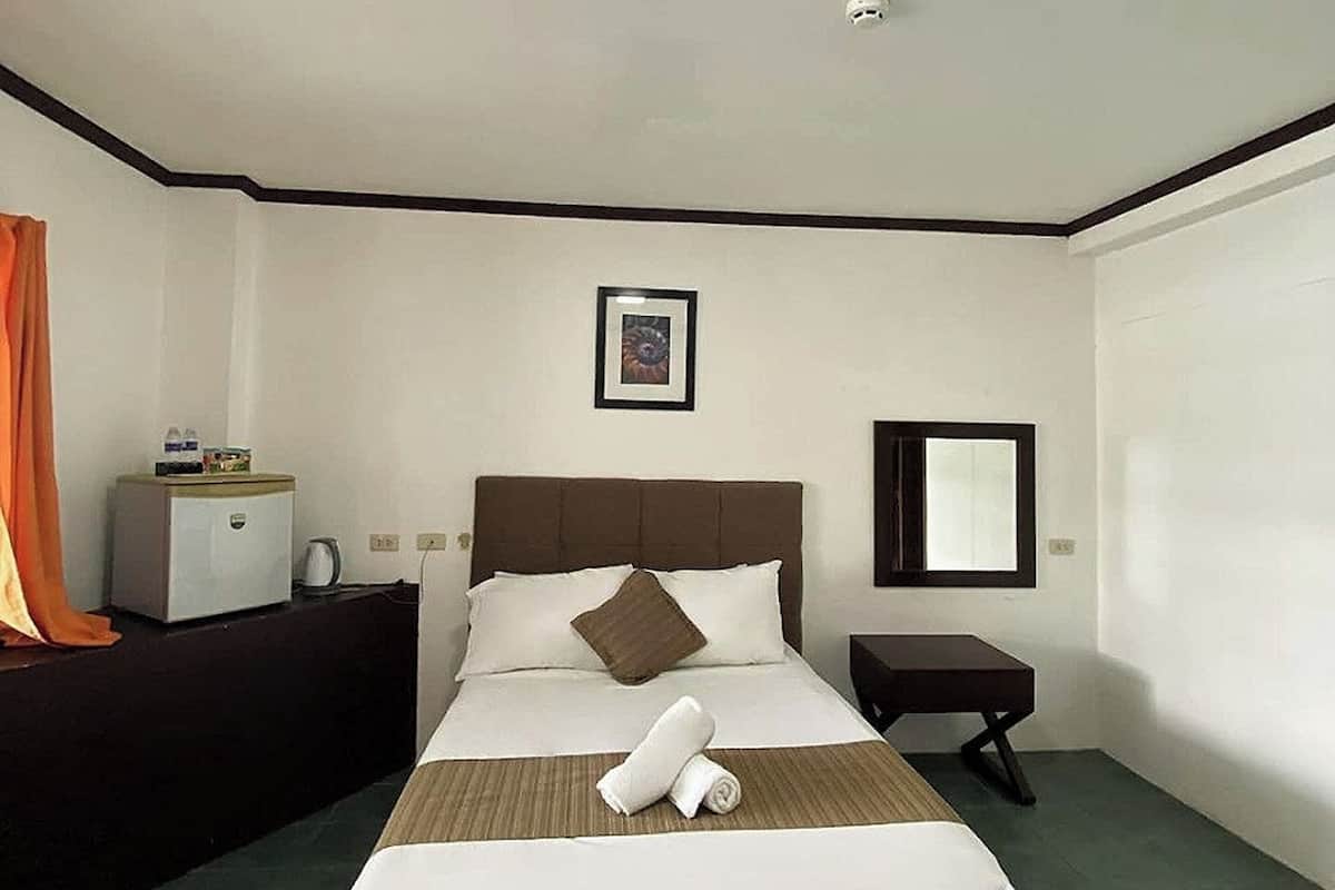 A hotel room with a bed, a bedside table, a nightstand, a mirror, and a picture on the wall.