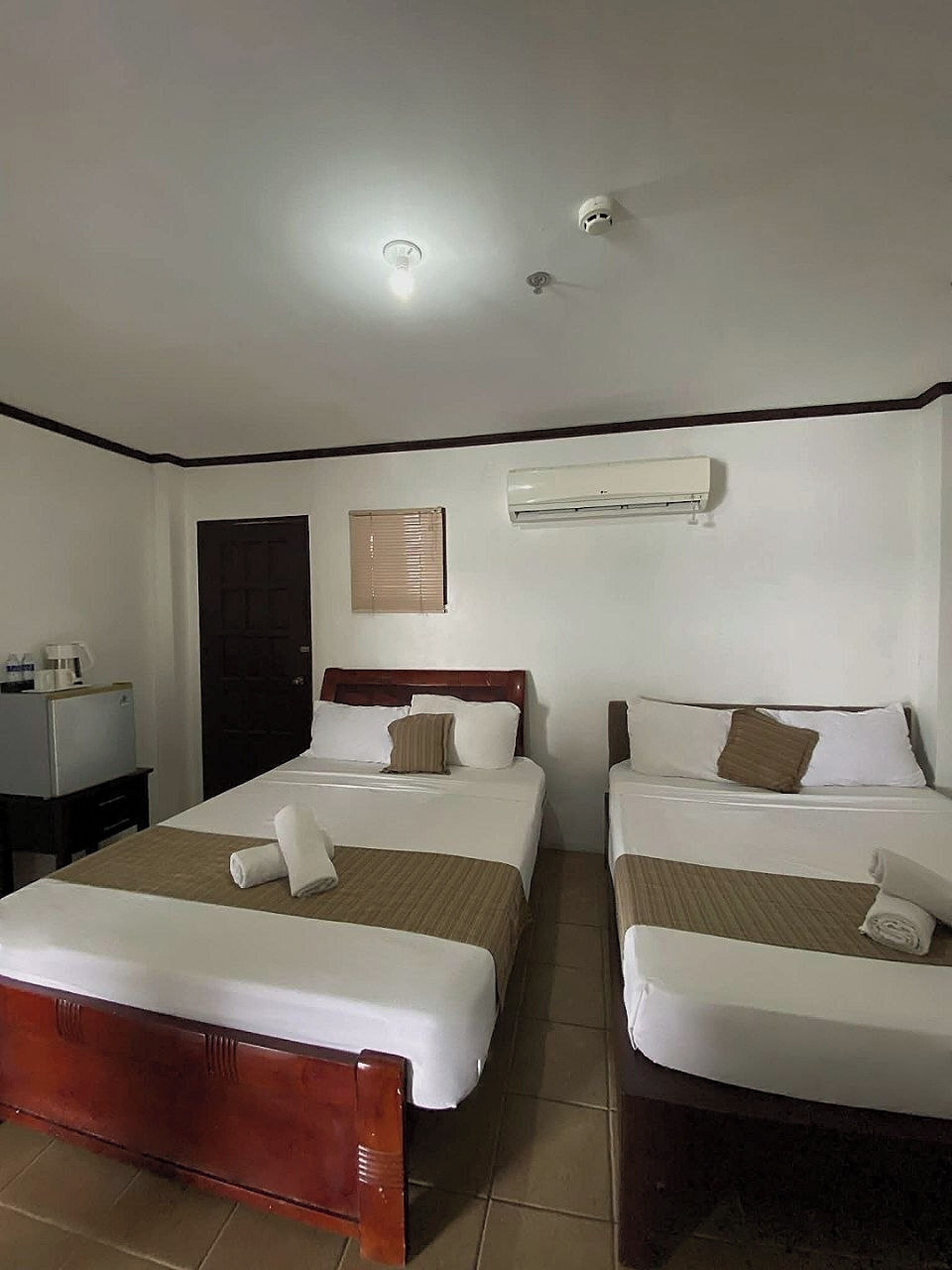 Habitación de hotel con dos camas, un escritorio, cafetera, puerta y aire acondicionado.