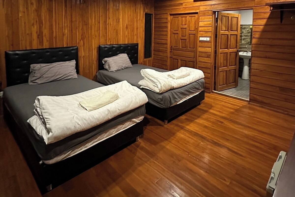 Ein Zimmer mit zwei Betten, Holzwänden und einer sichtbaren Badezimmertür.