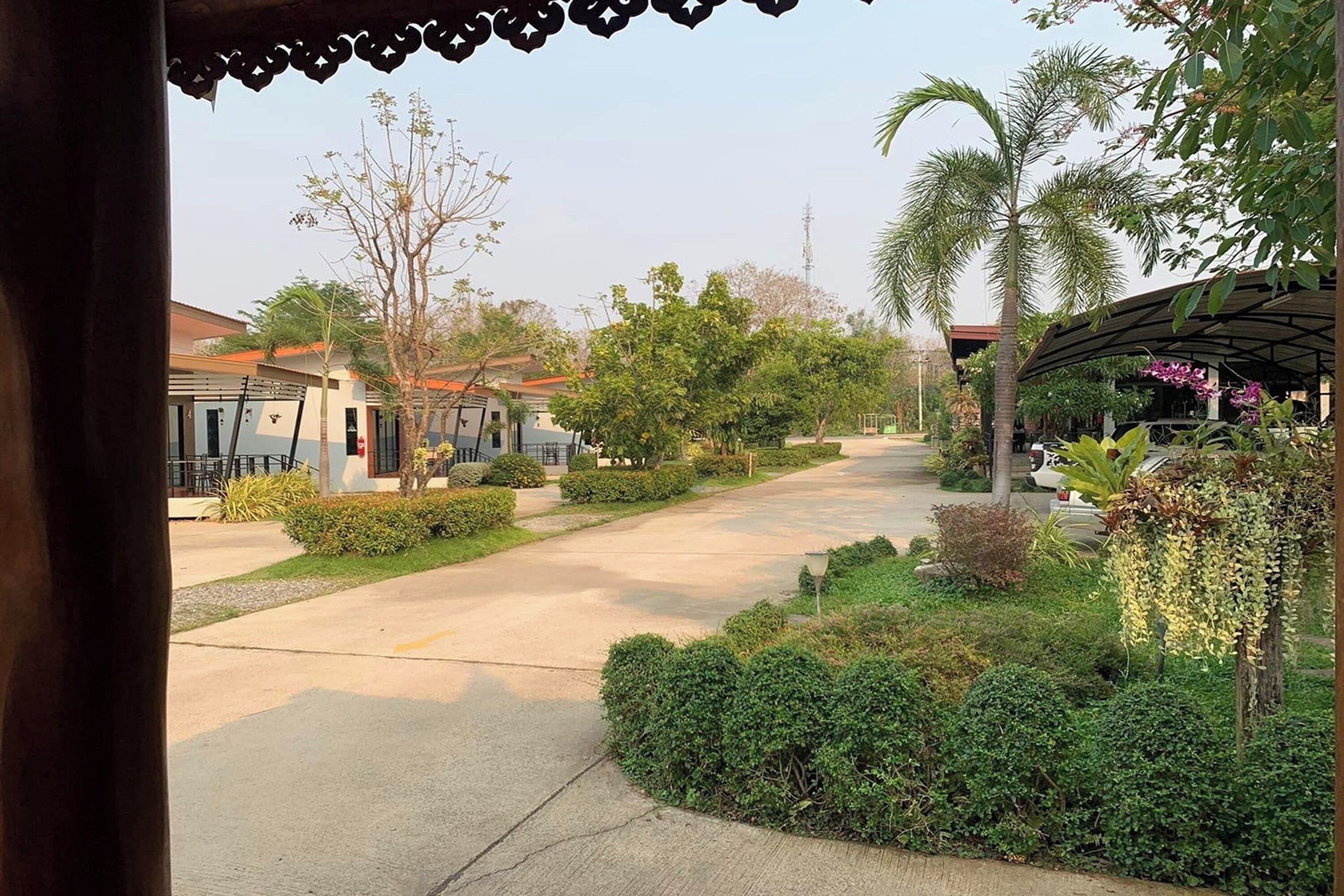 Una calle residencial con casas, un paseo techado y abundante vegetación.