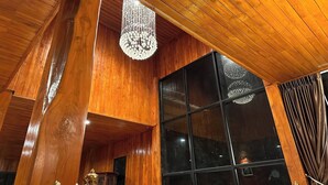 Un intérieur en bois avec une grande fenêtre, un lustre et une rambarde en métal.
