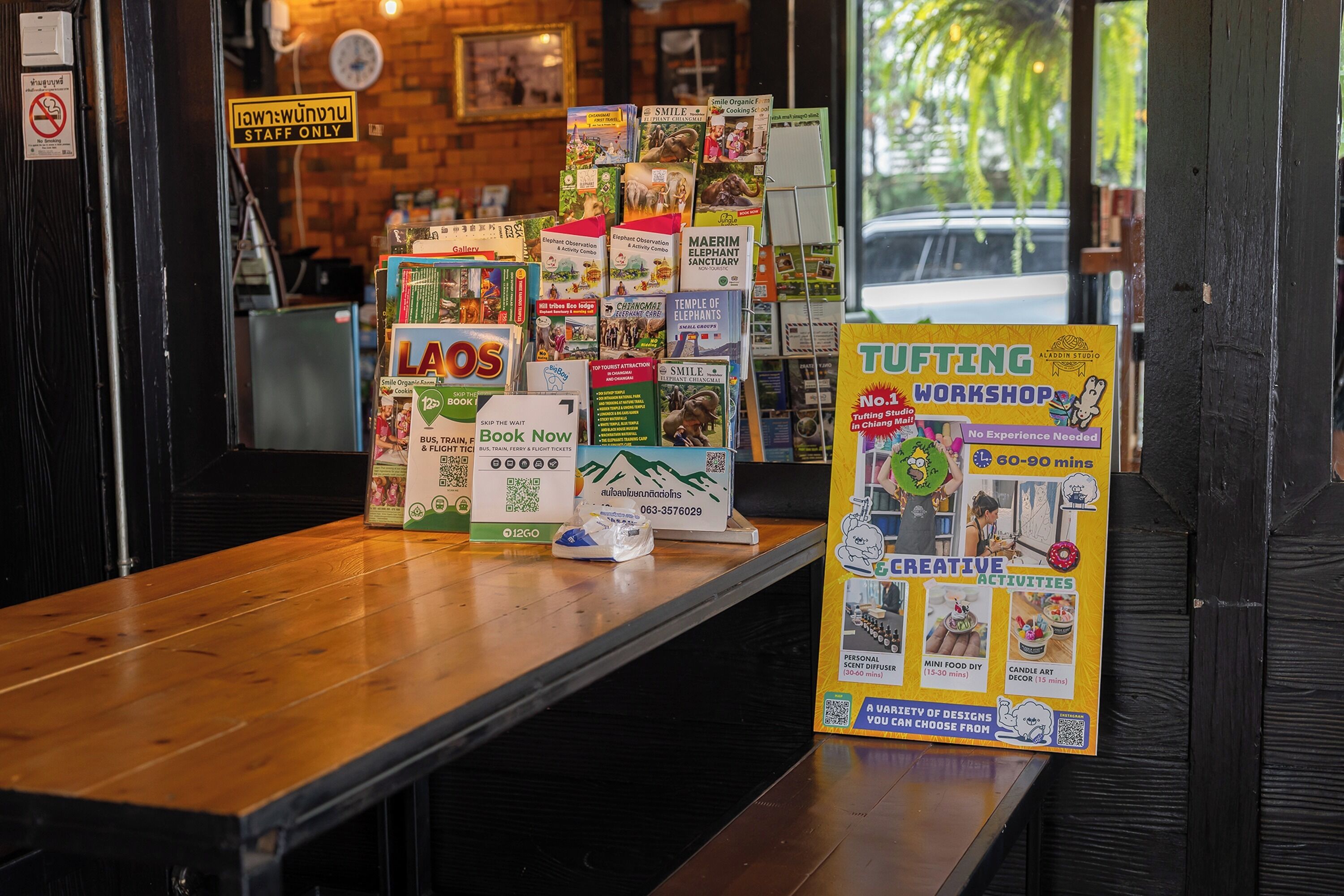 Plusieurs guides de voyage et une affiche promotionnelle pour un atelier de touffetage sont posés sur une table en bois.