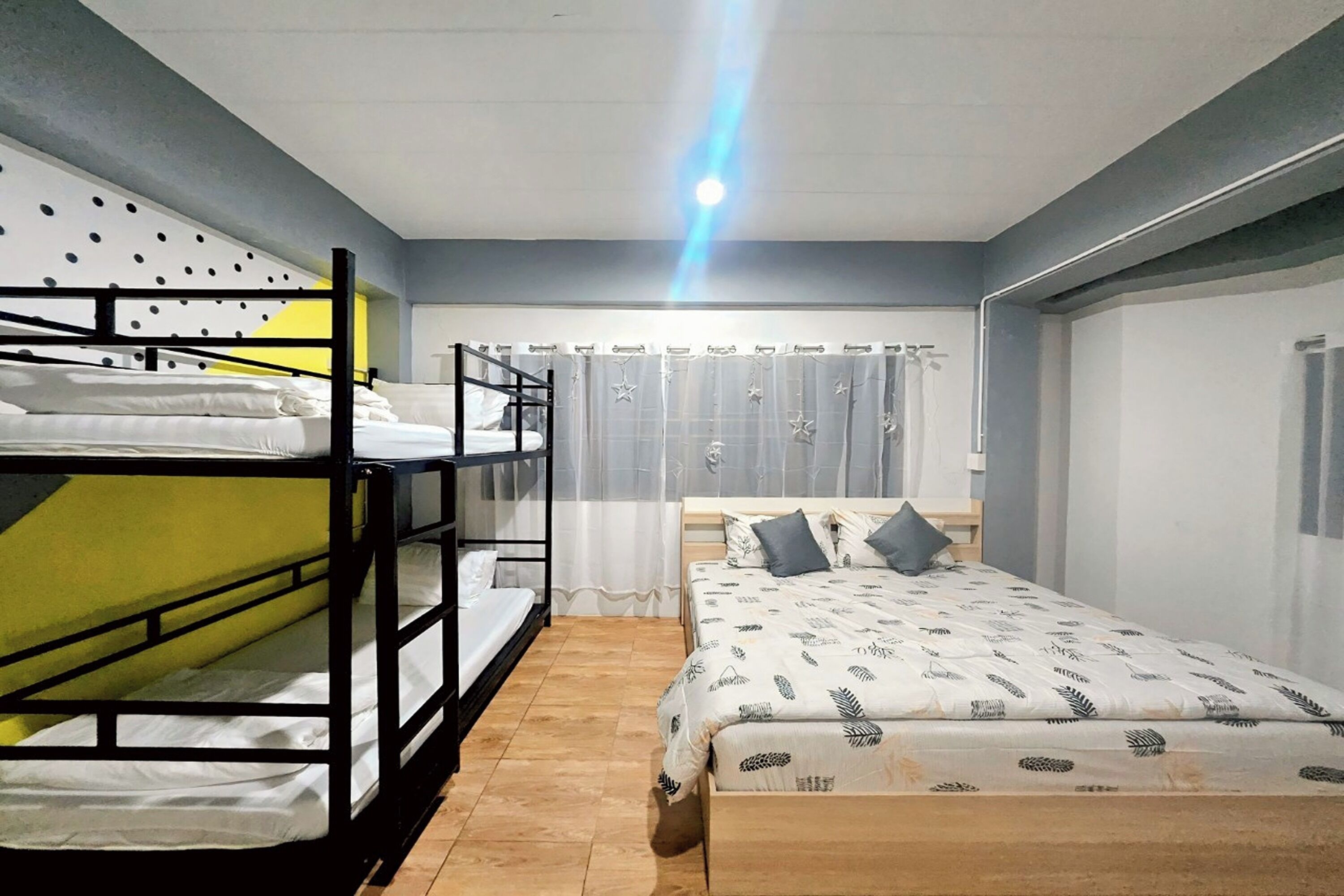 A dormitory room with bunk beds, a single bed, and a wardrobe.