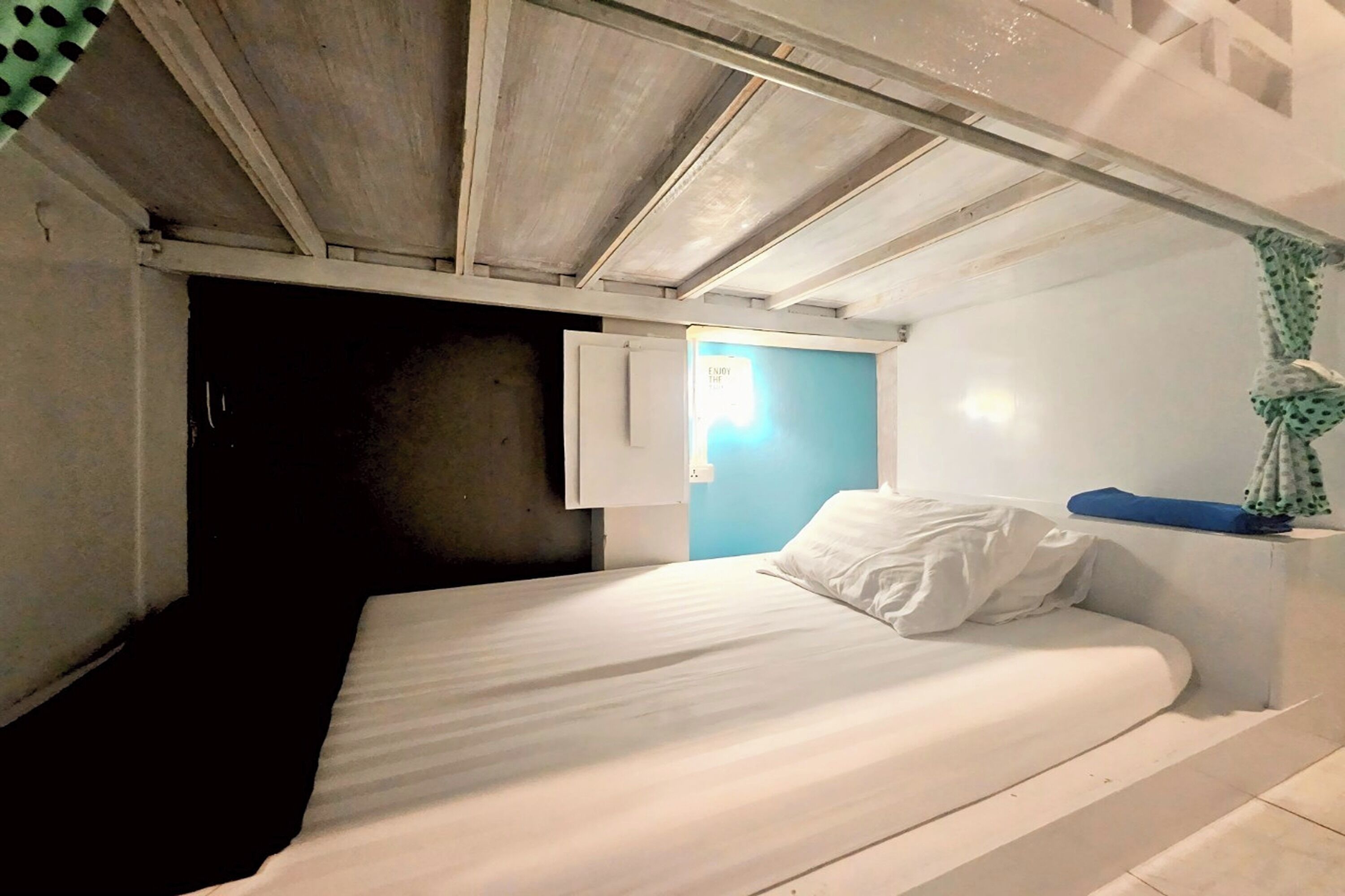 Ein kleines, schlichtes Zimmer mit einem Einzelbett, einem kleinen Fenster und einer Lampe.