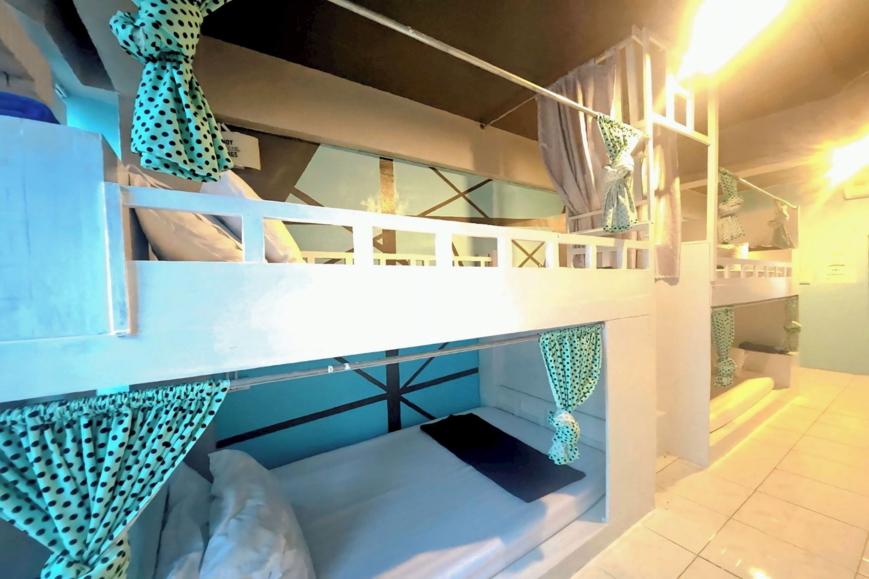A bunk bed room with a white frame, a lower bunk with a black mattress, and a ceiling fan.