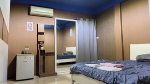 Une chambre comprenant un lit, une armoire, un petit réfrigérateur et un appareil de climatisation.