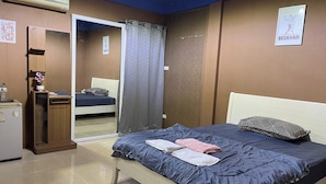 Une chambre à coucher avec un lit, une table de chevet, un miroir, une armoire et une affiche accrochée au mur.