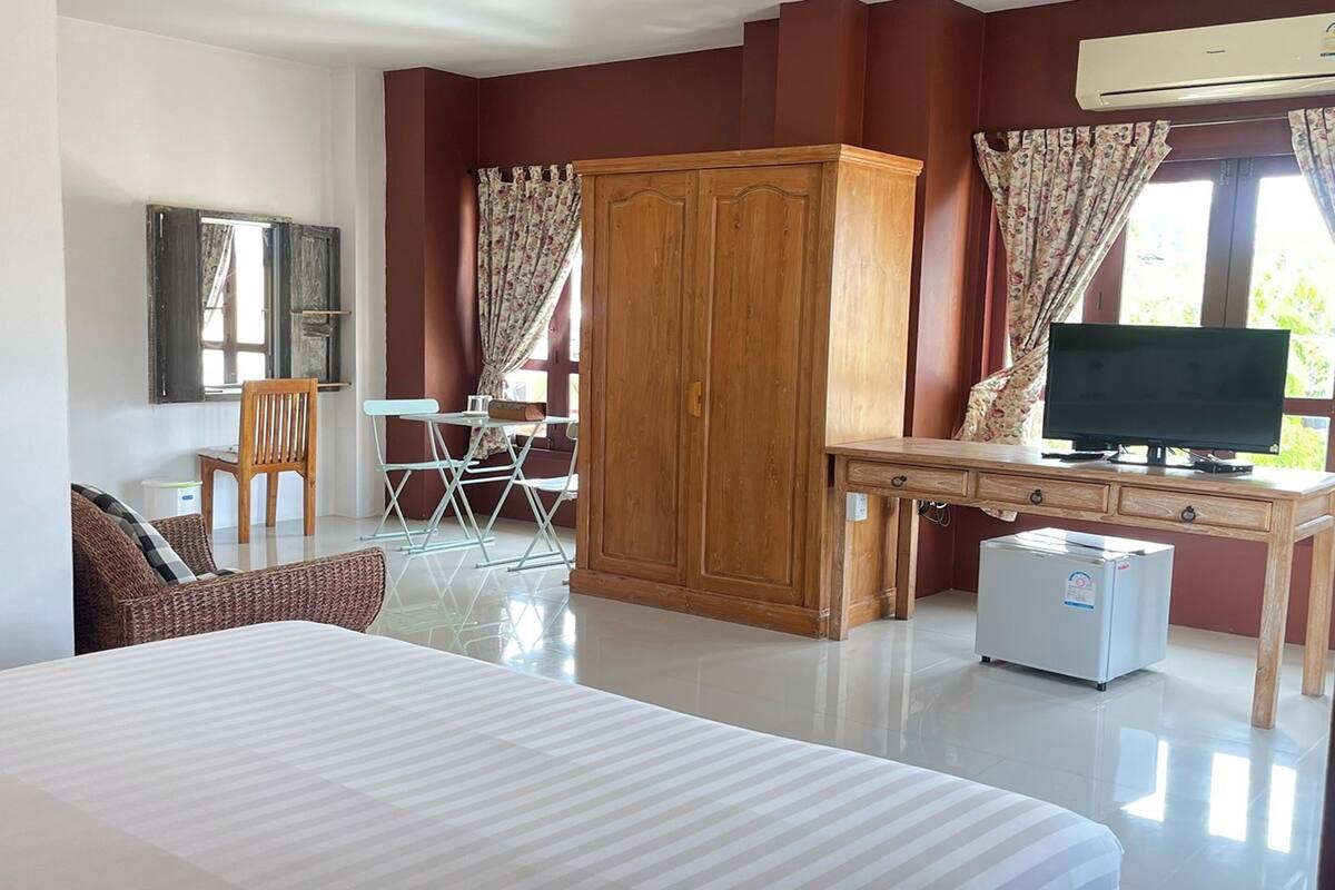 Une chambre d’hôtel comprenant un lit, un bureau avec une télévision, une armoire, une chaise et un petit réfrigérateur.