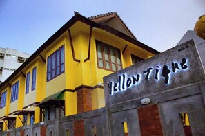 A yellow building with a sign that reads "Yellow Tiger." - Yellow Tique Hotel (Lampang)