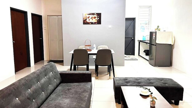 Una sala de estar moderna con un sofá gris, una mesa de comedor con sillas y una zona de cocina con un refrigerador y una pequeña mesa.