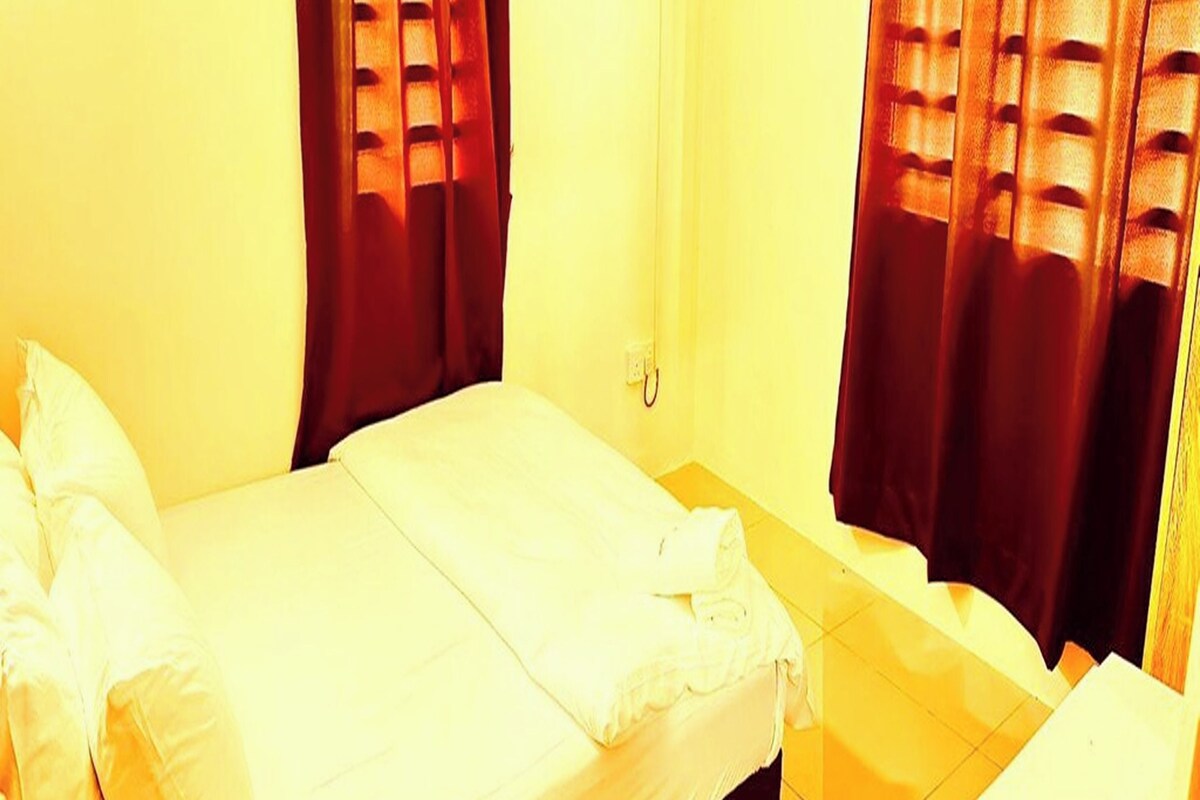 A room with a bed, a small table, and curtains.