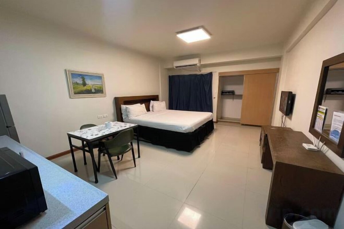 A hotel room with a bed, a desk, a chair, a TV, and a bathroom.