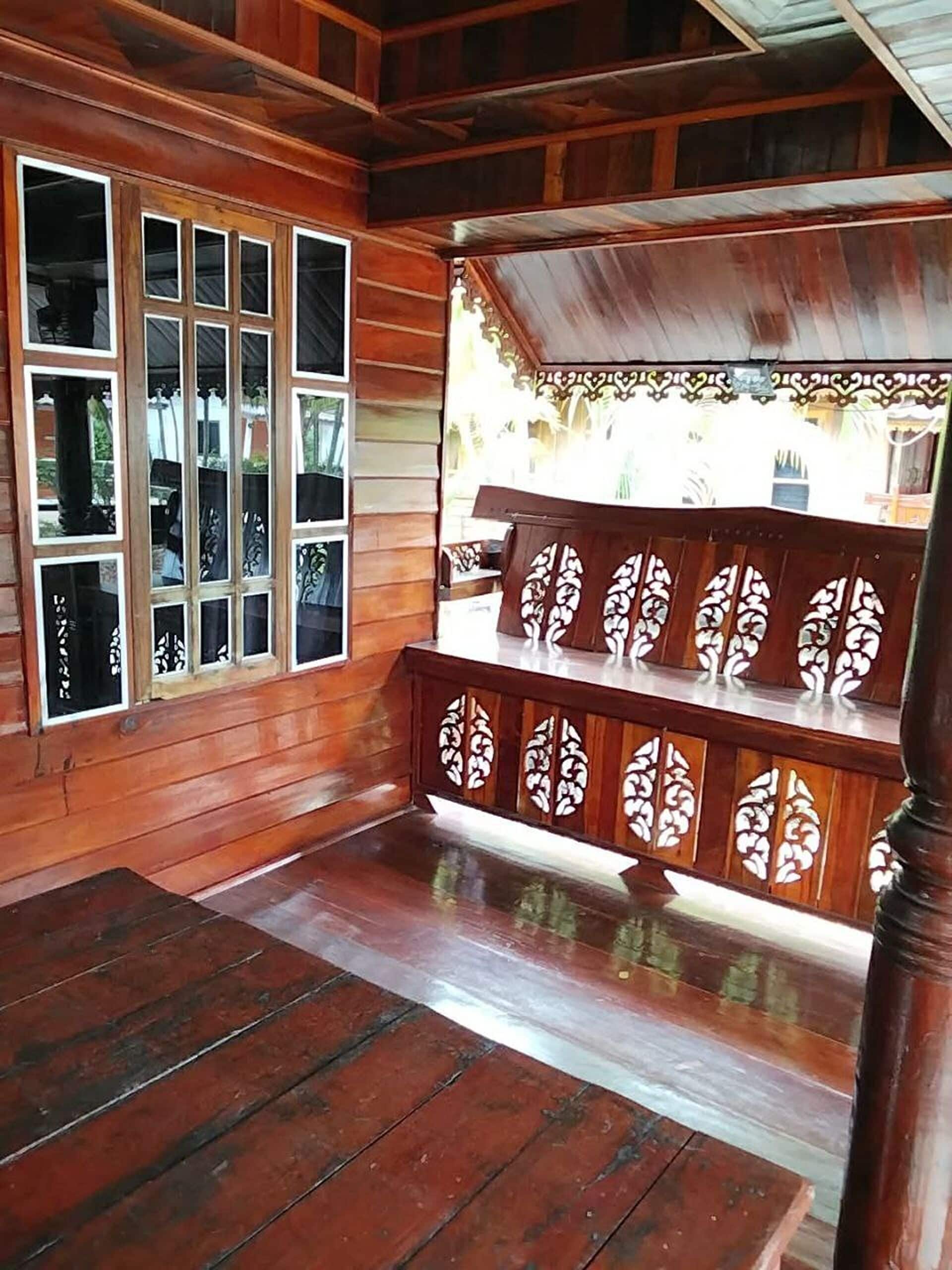 A wooden interior with a bench, a window with multiple panes, and a decorative railing.
