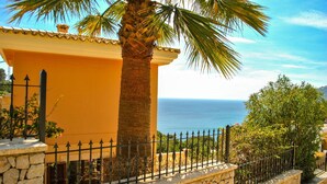 A coastal building with a stone wall and a metal fence, overlooking the sea. - Villa in Canyamel with Bay Views and Pool (Canyamel)