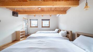 A bedroom with two beds, wooden beams, a ladder, and two windows.