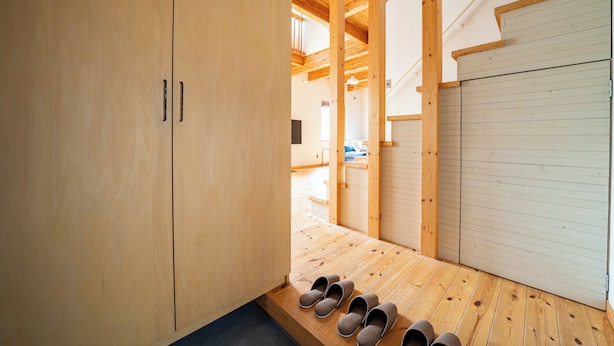 Un intérieur en bois avec un porte-chaussures, un escalier et une porte fermée.
