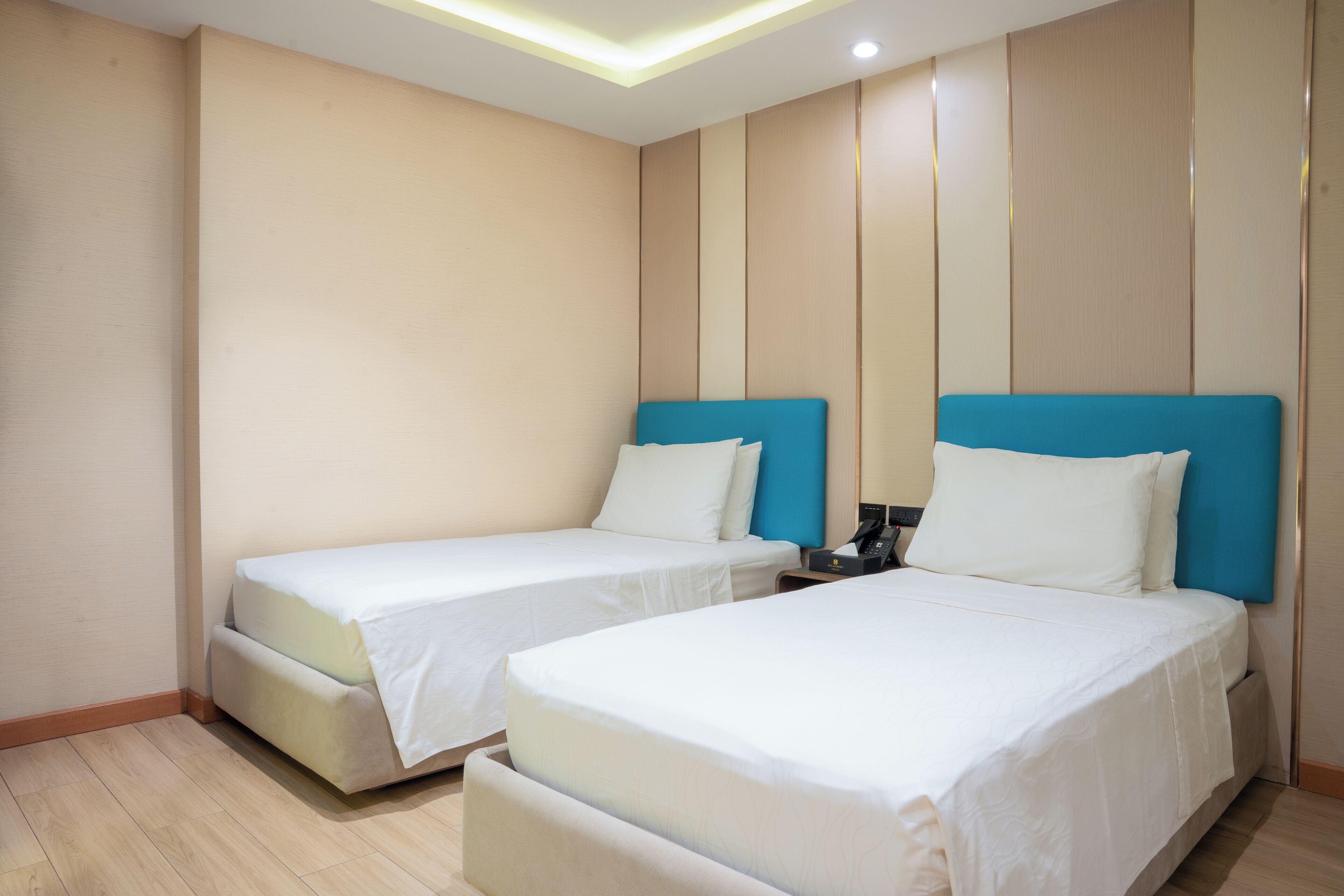 Una habitación de hotel con dos camas, una mesita de noche y una lámpara del techo.