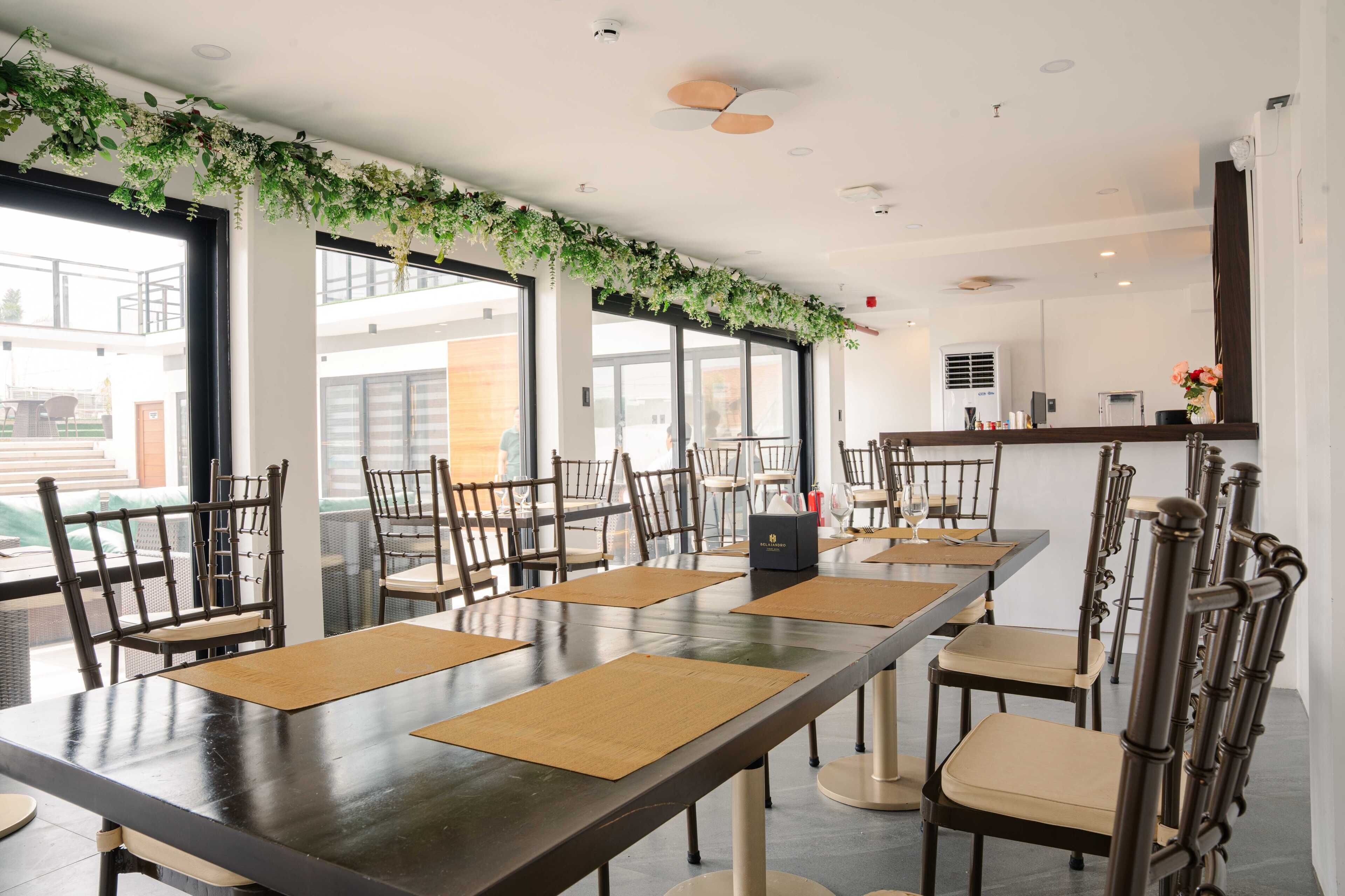 A conference room with a long table, chairs, and a ceiling adorned with greenery.