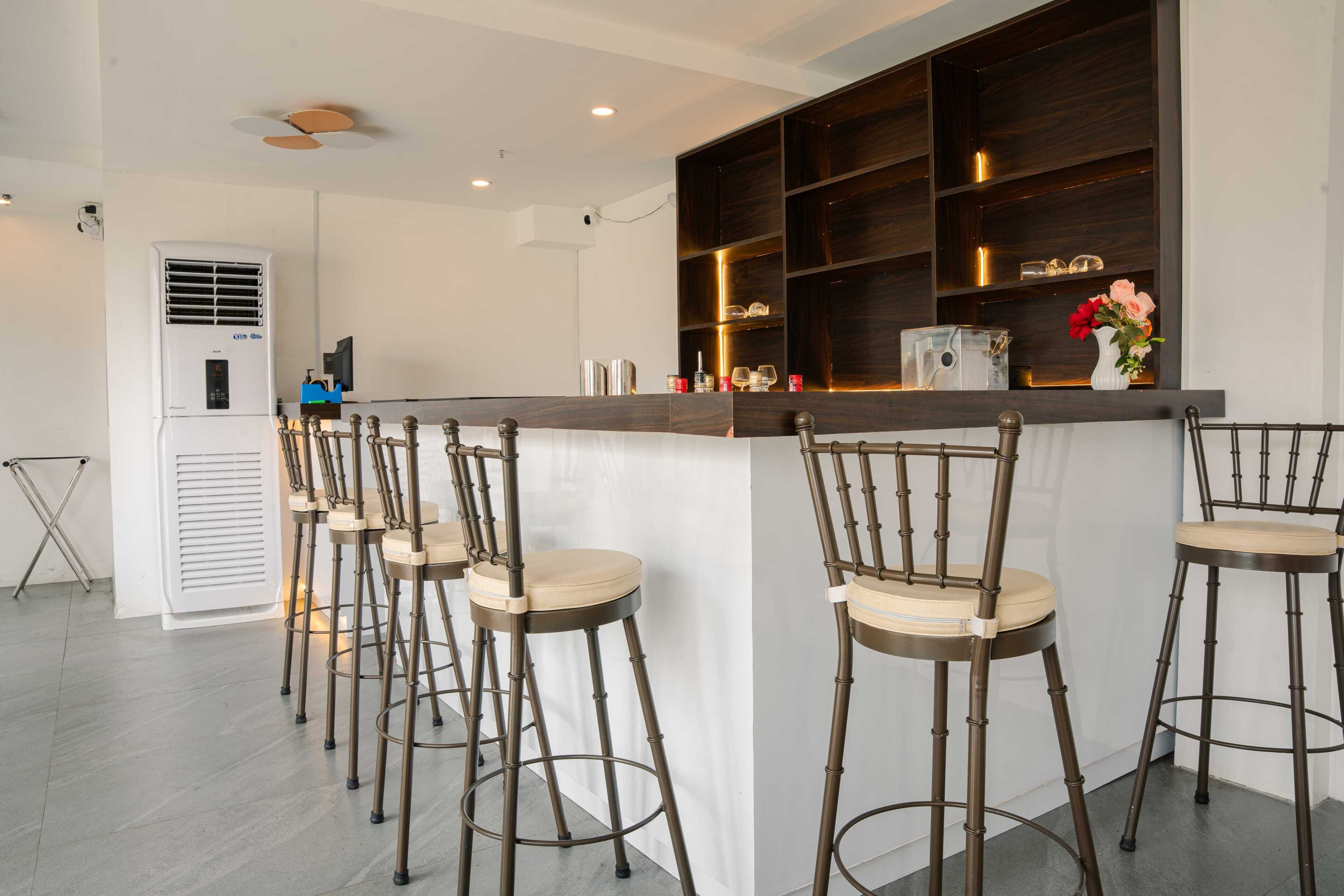 A bar area with multiple stools, a counter, and a shelf with items.