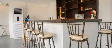 A bar area with multiple stools, a counter, and a shelf with items.