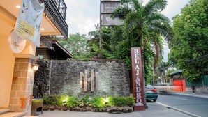 A hotel entrance with a stone wall, a sign for 'BELAJ ANDRO HOTEL,' and a street view with a car passing by. - Sunday Belajandro Hotel (Angeles City)