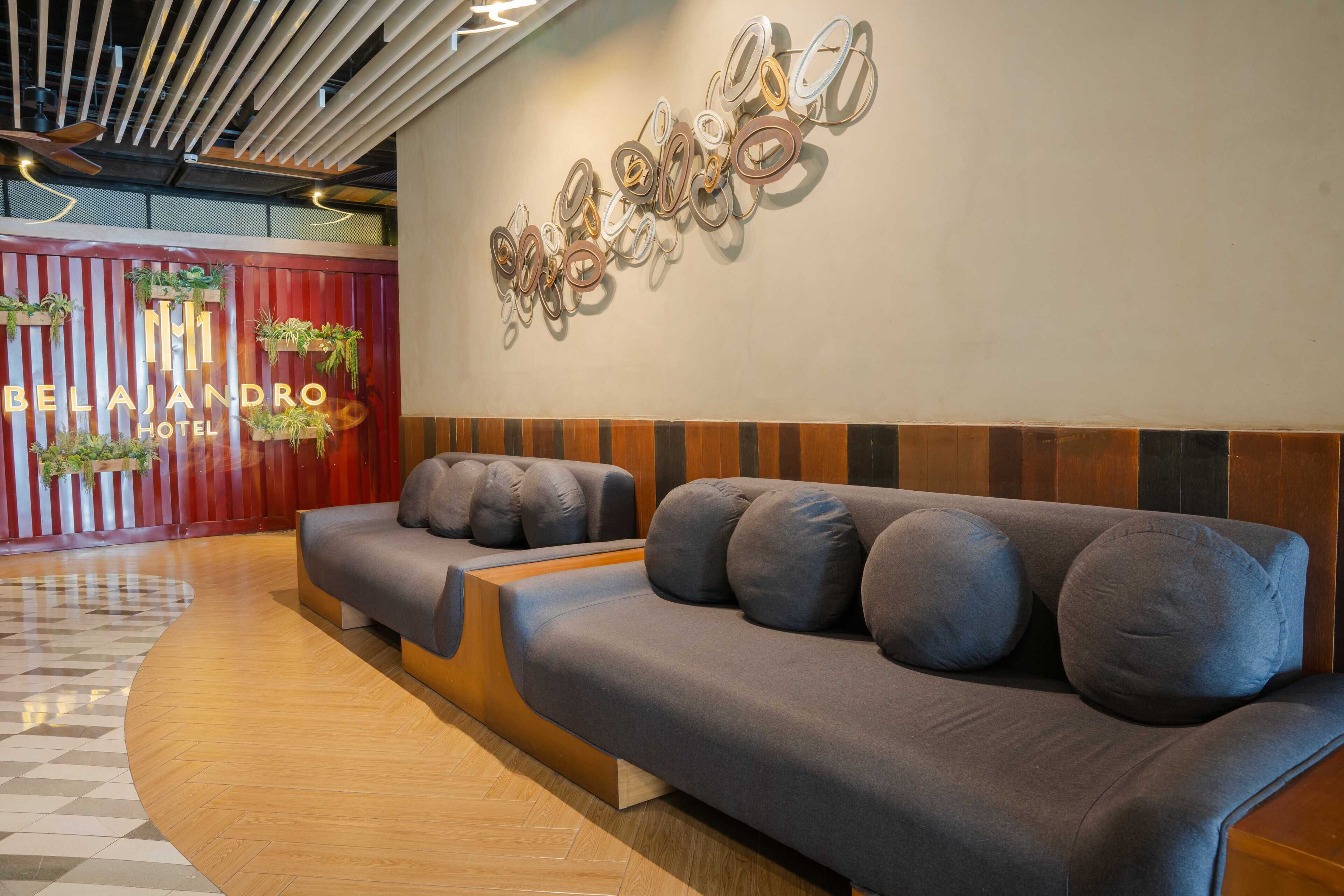 En hotellobby med en receptionsdisk, en modern soffa och en vägg med en dekorativ skylt.