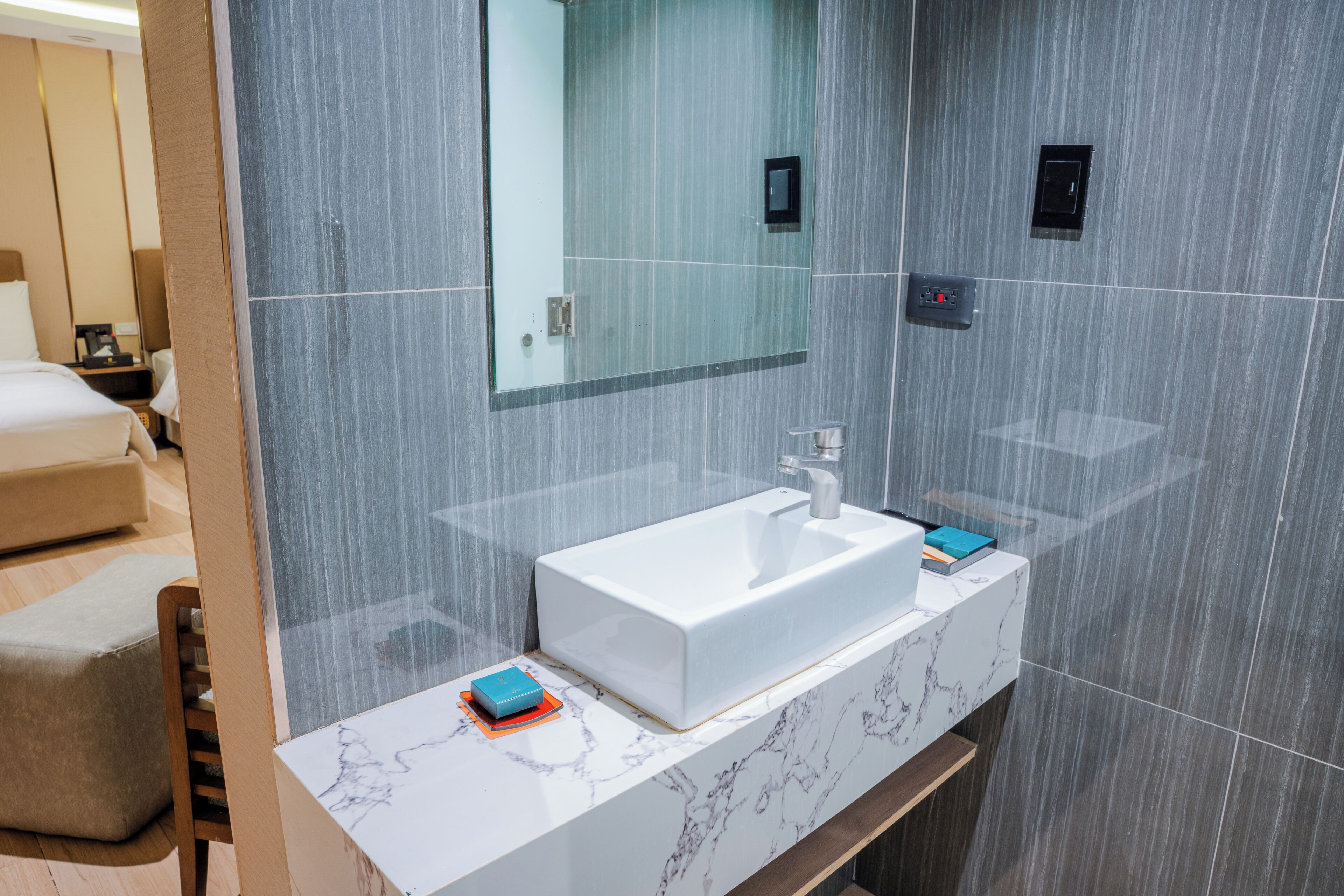 Une salle de bain moderne avec un lavabo blanc, un grand miroir et un comptoir en marbre.