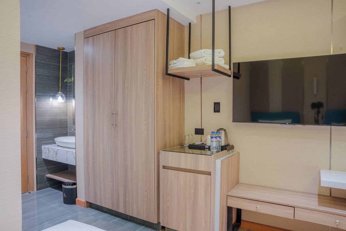 A modern bathroom with a wooden vanity, a glass sink, a mirror, and a towel rack.