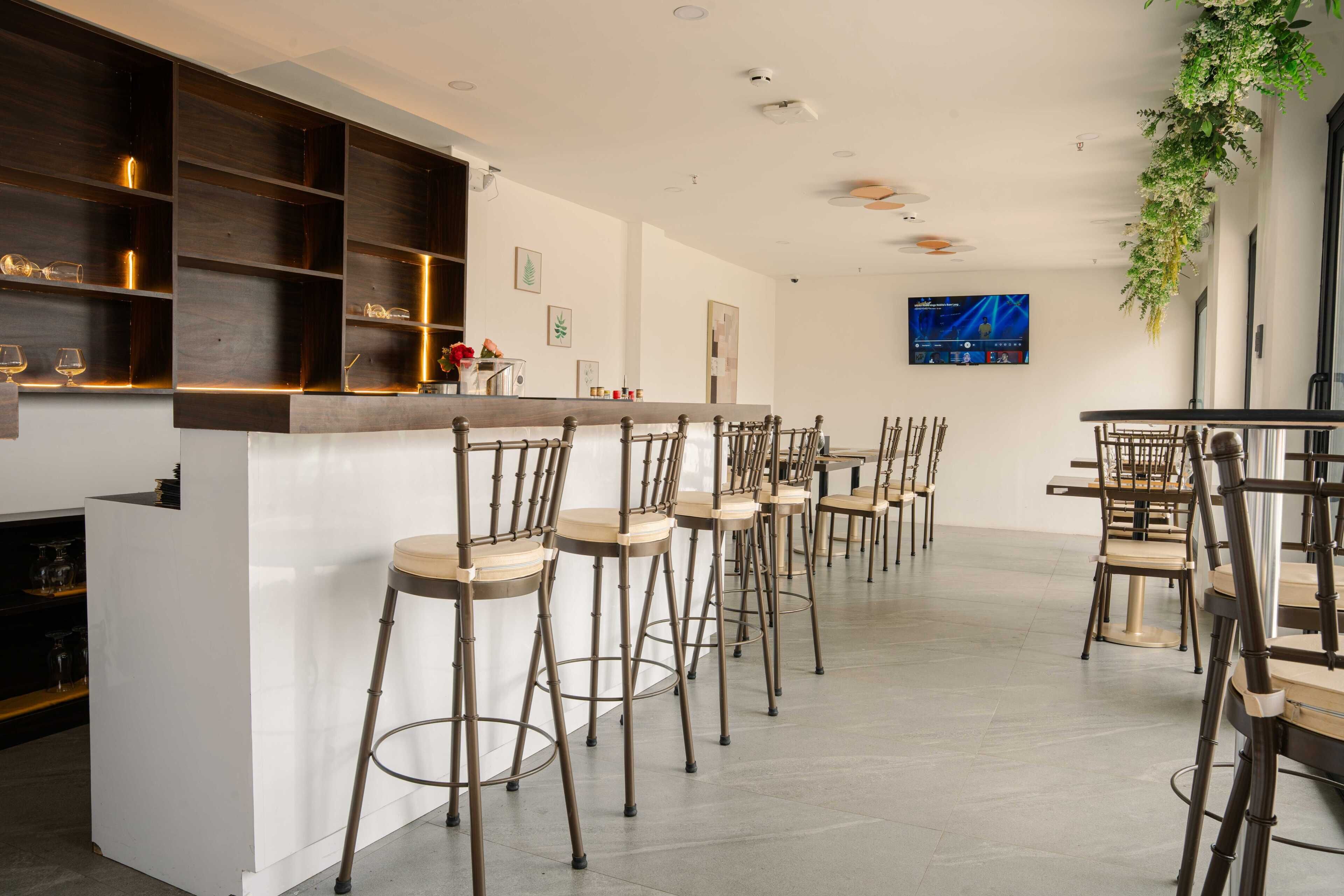 A bar area with high stools, a counter, and a television screen.