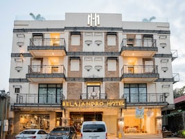 A multi-story hotel with balconies, a sign reading 'BELAJANERO HOTEL,' and a van parked in front.