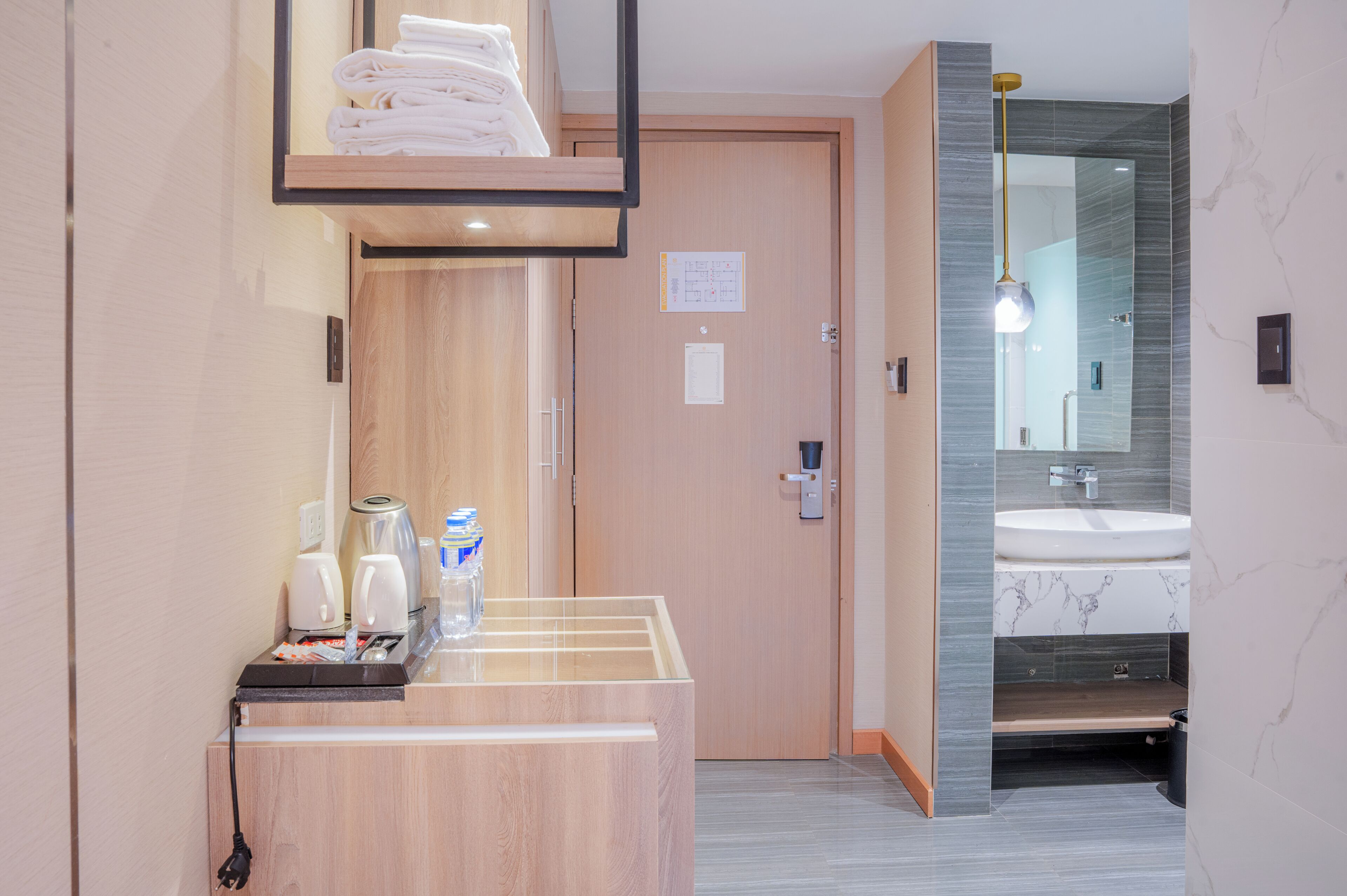 A hotel bathroom with a wooden vanity, a sink, and a mirror.