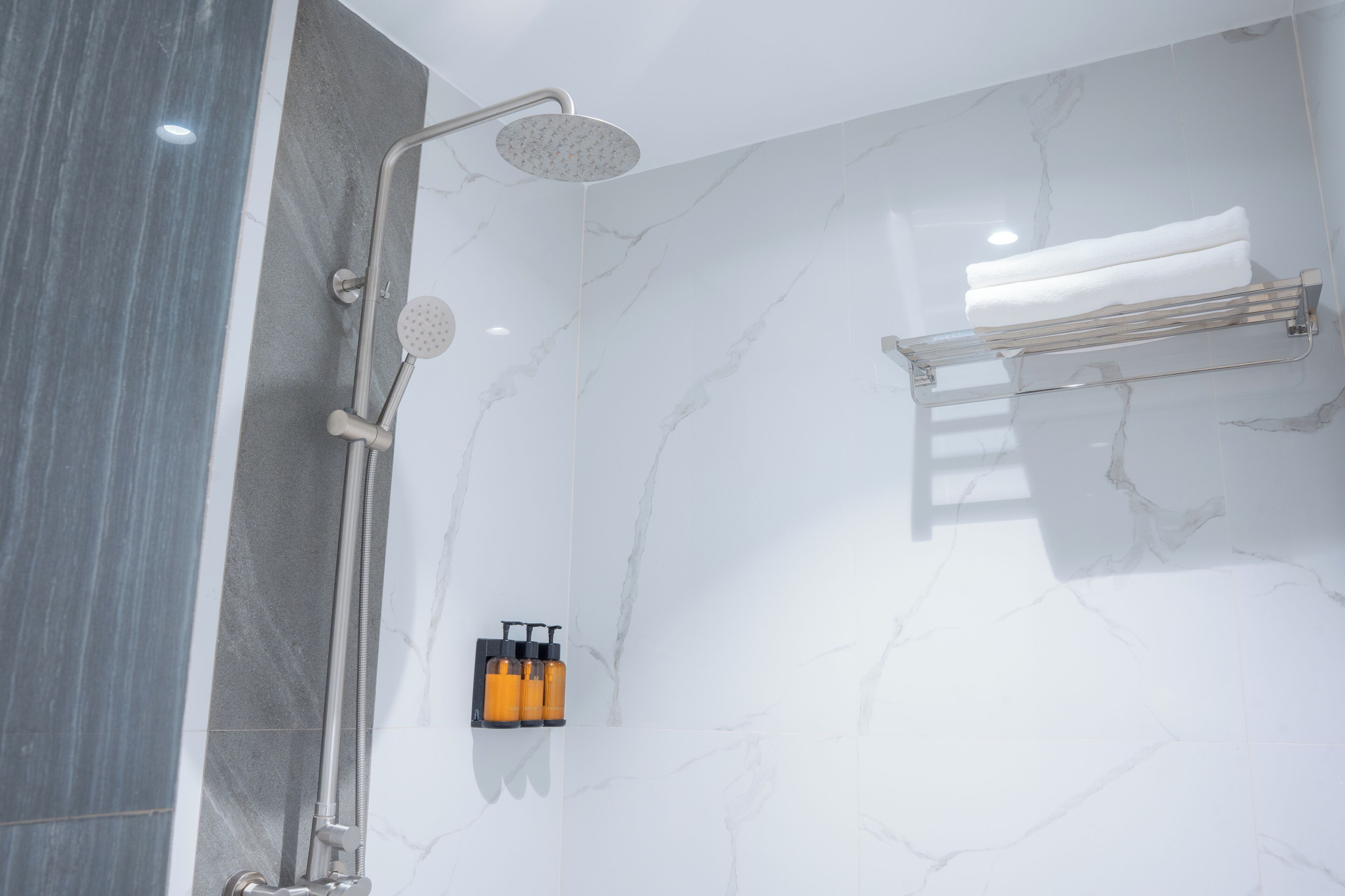 A modern bathroom with a shower, a towel rack, and a soap dispenser.