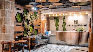 A hotel reception area with a modern design, including a reception desk, seating area, and decorative plants. - Sunday Belajandro Hotel (Angeles City)
