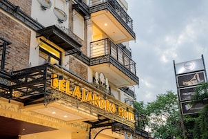 A hotel with ornate balconies, a prominent sign reading 'BELAJANDRO HOTEL,' and a signboard advertising 'imerex' and 'CIRCUITMINING.'