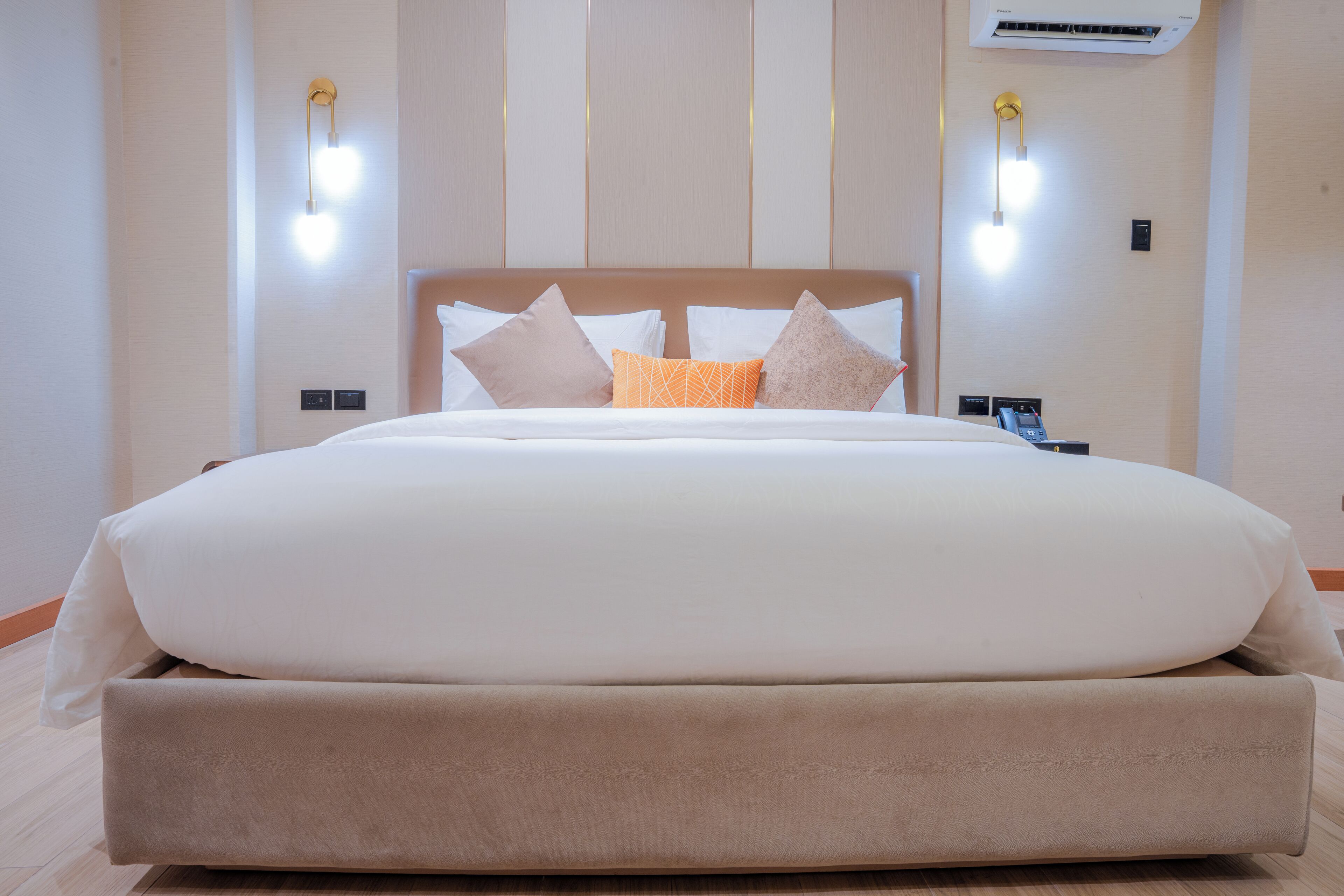 Ein großes Bett mit Holz-Kopfstück, zwei Nachttische und Wandleuchten.