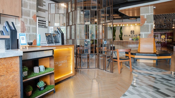 A modern hotel lobby with a reception desk, seating area, and a staircase. - Sunday Belajandro Hotel (Angeles City)