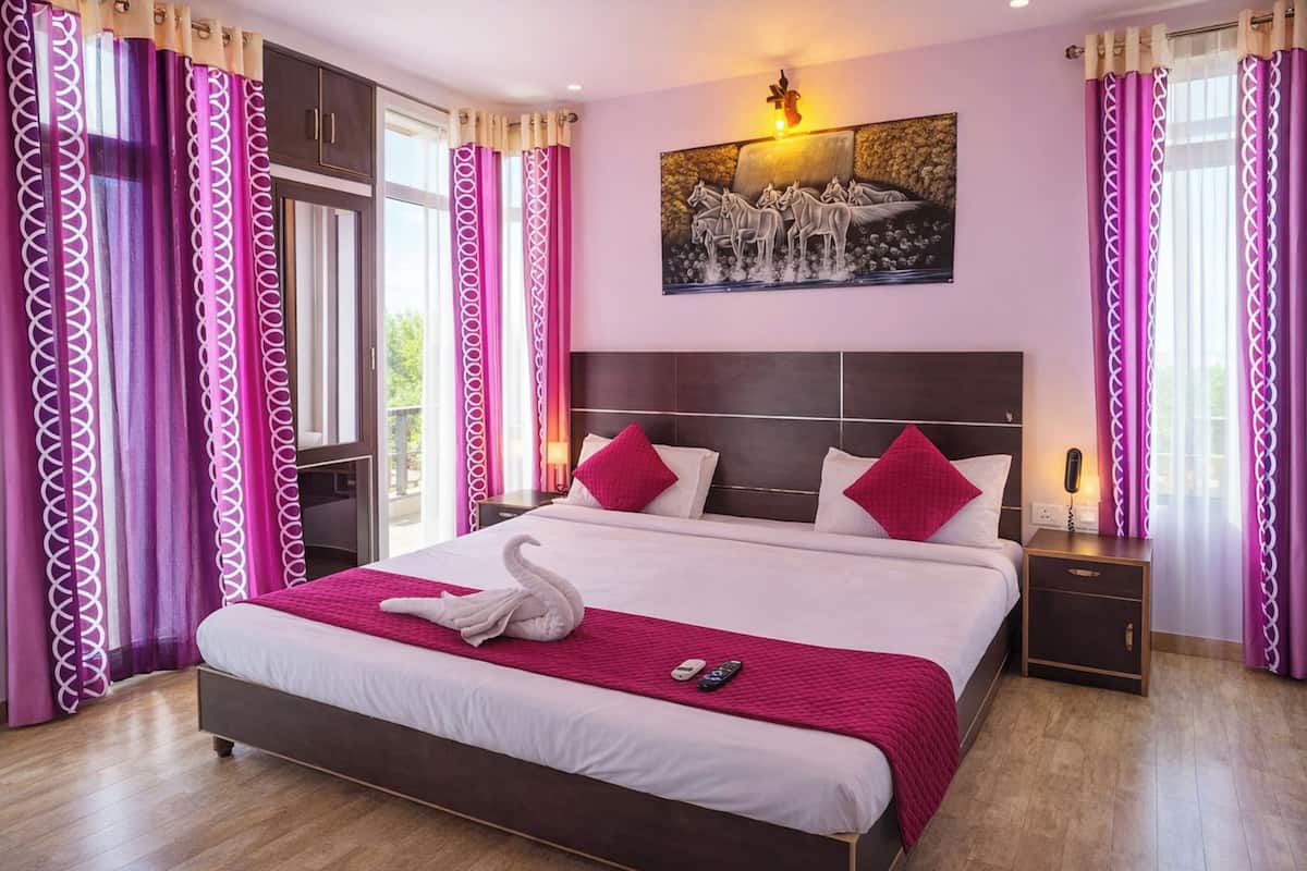 A hotel room with a large bed, a nightstand with a phone, and a painting on the wall.