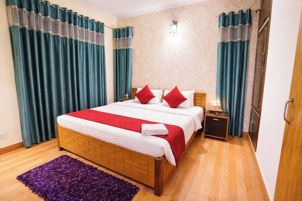 A bedroom with a wooden bed, red pillows, a purple rug, and teal curtains.