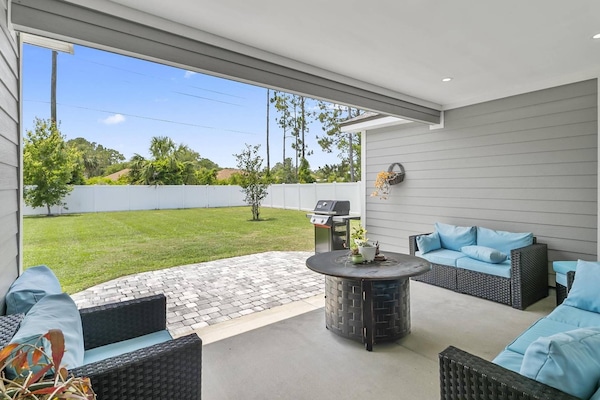 Spacious outdoor patio with ample seating, a gas fire pit, and BBQ grill—all set in a private, fenced backyard ideal for relaxing and entertaining.