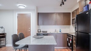 A modern kitchen with a central island, dark cabinets, and stainless steel appliances. - Luxurious 2Bedroom 1Bath Condo Walk to Square One Mall YYZToronto Pearson 1 pkng (Mississauga)