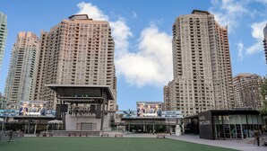 Un área urbana moderna con rascacielos, un campo deportivo y un edificio con la leyenda "HAZEL M'CALLION".