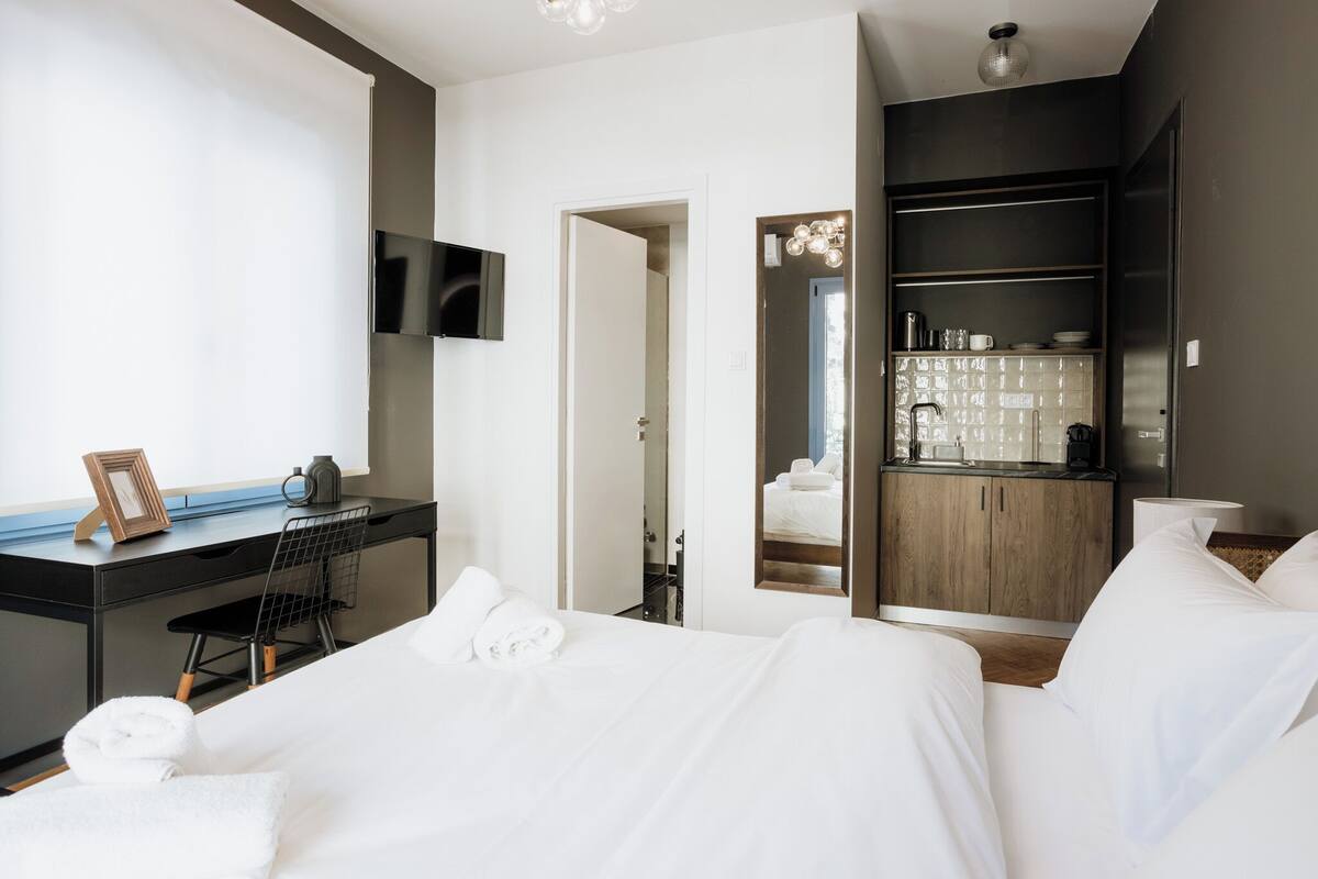 Moderni hotellihuone, jossa on sänky, työpöytä, tuoli, televisio ja minibaari.