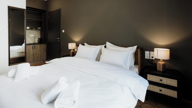 Una habitación de hotel con una cama grande, dos mesitas de noche con lámparas, un armario y un espejo.